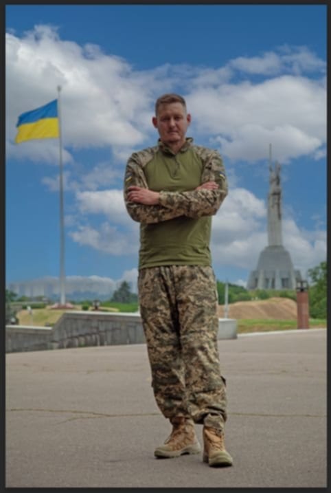 Krigsveteranen Denys står foran det ukrainske flag i hovedstaden, efter han er vendt hjem til Ukraine fra Danmark.